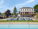 Beautiful swimming pool area with lounge chairs and umbrellas at Independence Green Apartments.