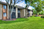 Exterior view of a two-bedroom, fully renovated townhome at Park at Murano, surrounded by greenery in Fort Myers, FL.