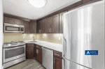 Modern kitchen with stainless steel appliances, dark cabinetry, and quartz countertops in a spacious apartment.