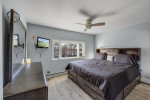 Bright bedroom featuring a bed with storage, wall-mounted TV, and large window in a semi-attached house in Brooklyn.