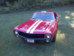 1968 AMC AMX classic muscle car in striking red with white stripes, showcasing its powerful 401 engine.
