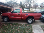 Side view of a 2005 red Toyota Tacoma truck parked in a driveway