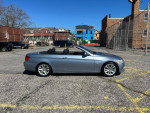 2000 BMW 3 Series 328i convertible parked in a lot with a clear sky, showcasing its sleek design and low mileage.