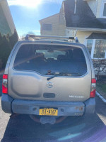Rear view of a 2003 Nissan Xterra for sale, color champagne, showing potential for repair or parts.