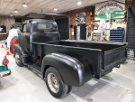 Classic Ford pickup truck with a black finish in a vintage car garage setting.