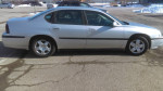 Side view of a clean, silver 2001 Chevrolet Impala parked on a driveway.