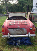 1962 MG Midget 2-door convertible rear view, for parts or restoration, parked on grass.