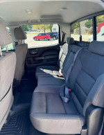 Interior of GMC Sierra showing spacious back seat with grey cloth upholstery and seatbelts.