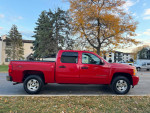Red 2011 Chevrolet Silverado 1500 LT crew pickup truck parked outdoors, showcasing sleek design and sturdy build.