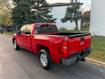 2011 Chevrolet Silverado 1500 LT 4WD in red, parked on the street, showcasing its crew cab and clean exterior.