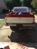 Rear view of a 1969 GMC 1500 truck parked in a garage, showcasing its classic design and restoration parts.