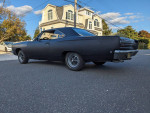 1968 Plymouth GTX 440 in matte black finish parked on the street with a house in the background