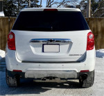 Rear view of a 2015 Chevrolet Equinox LTZ in white, showcasing chrome accents and winter tires.