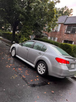 2010 Subaru Legacy parked on a rainy street, featuring silver color and AWD capabilities.