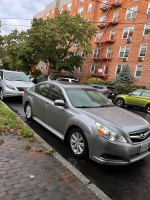 2010 Subaru Legacy parked on a street, showcasing its sleek design and silver color.