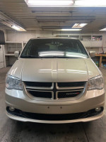 Front view of a 2013 Dodge Grand Caravan in a garage with clean exterior and lighting.