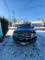 Front view of a 2010 Ford Expedition parked in snow, featuring 3rd row seating and 114,000 miles.