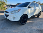 2011 Hyundai Tucson with black rims parked in a gravel area, showcasing its clean exterior and modern design.