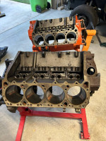 1969 Plymouth Roadrunner engine block with surface rust, stored for over 20 years, on a stand in a garage.