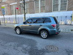 2009 Subaru Forester 2.5X in blue parked on street, showcasing its clean exterior and all-wheel drive capability
