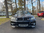 Black 2011 BMW 335i xDrive in driveway, showcasing its sporty front design and custom modifications.
