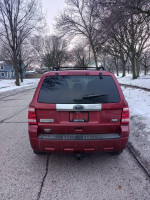 Red Ford Escape parked on snowy street, showcasing rear view and no visible issues.