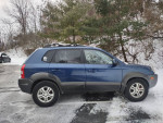 2005 Hyundai Tucson 4x4 parked in snow with clean body and roof rack, showing backup camera and Bluetooth features.