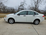 2011 Ford Focus SE white sedan parked on a concrete driveway, showcasing its low mileage and excellent condition.