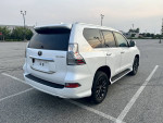 Rear view of a 2020 Lexus GX 460 4WD in white pearl color, parked in an empty lot with clean exterior.