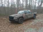 1997 Dodge Dakota Sport 4WD truck in camouflage paint parked on gravel surrounded by autumn leaves