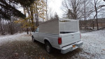 1991 Ford F150 truck parked in snowy landscape with camper shell and two gas tanks