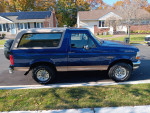 1996 Ford Bronco Eddie Bauer in Midnight Blue parked on the street with autumn foliage around.