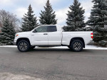 2019 Toyota Tundra 4x4 truck in pristine condition, parked on a snowy road with evergreen trees.