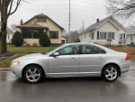 2009 Volvo S80 T6 AWD silver sedan parked on a rainy street, showcasing its sleek design and excellent condition.