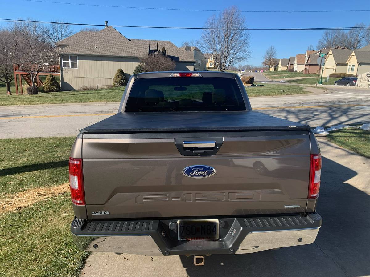 Rear view of a 2018 Ford F150 XLT in brown color, showcasing the bed cover and LineX sprayed bed liner.