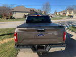 Rear view of a 2018 Ford F150 XLT in brown color, showcasing the bed cover and LineX sprayed bed liner.