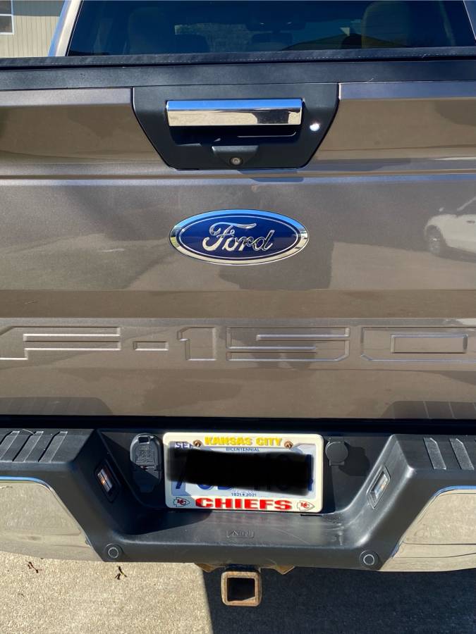 2018 Ford F150 XLT rear view with license plate and truck emblem, showcasing its brown color and features.