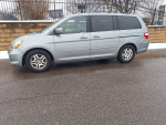 Side view of a silver Honda Odyssey EXL in excellent condition parked on a snowy road.