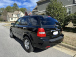2009 Kia Sorento with 121,000 miles parked on a street, featuring a black exterior and new tires.