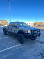 2005 Ford F-350 King Ranch 4x4 pickup truck with aftermarket modifications parked in a lot.