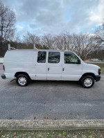 2008 Ford E-150 cargo van parked, features ladder racks and storage bins, great condition, 113,000 miles.