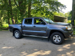 2013 Toyota Tacoma PreRunner RWD in gray, double cab, with a 5-foot bed parked in a natural setting.
