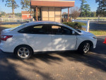 Side view of a white 2014 Ford Focus with minor damage and 63,000 miles for sale.