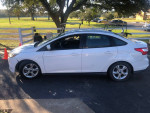 2014 white Ford Focus with minor exterior damage, parked in a scenic outdoor setting