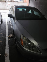 Damaged 2005 Honda Accord parked, showing the rear side with missing tire and airbag deployment signs.