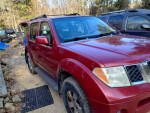 2007 Nissan Pathfinder in maroon color with tan interior, parked on a gravel driveway, showcasing its 4x4 capability.