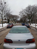 Silver Chevrolet Malibu parked on a snowy street, ready for sale, showcasing its well-maintained exterior.