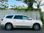 Side view of a 2011 Buick Enclave CXL2 in white with chrome wheels, parked against a metal fence.