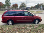 2005 Chrysler Town & Country minivan in burgundy color parked on a street with fallen leaves.