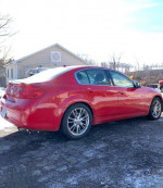 2010 Infiniti G37x AWD in red parked outdoors, featuring sleek design and sporty alloy wheels.